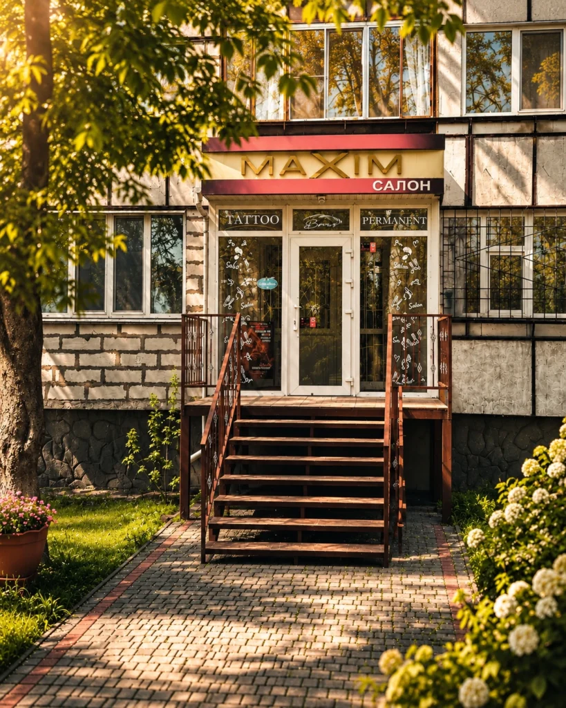 Вхід до салону MaXiM у Миколаєві: сходи з поручнями, вивіска MAXIM САЛОН над скляними дверима з написами Tattoo і Permanent